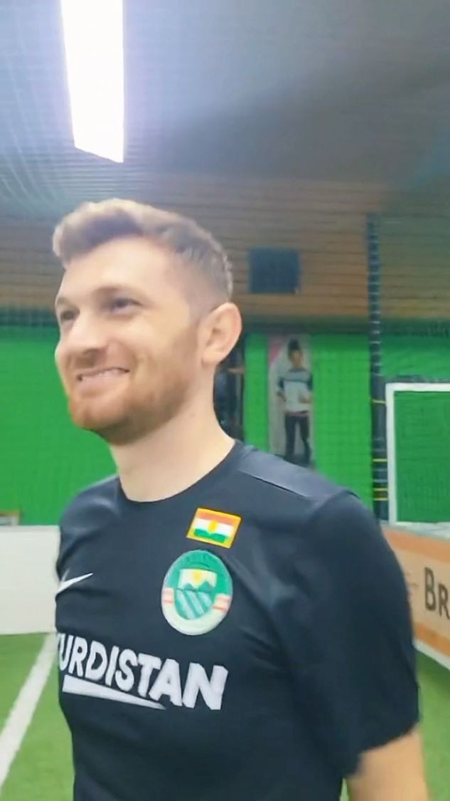 Young Kurdish man smiling in a Kurdistan shirt on the pitch